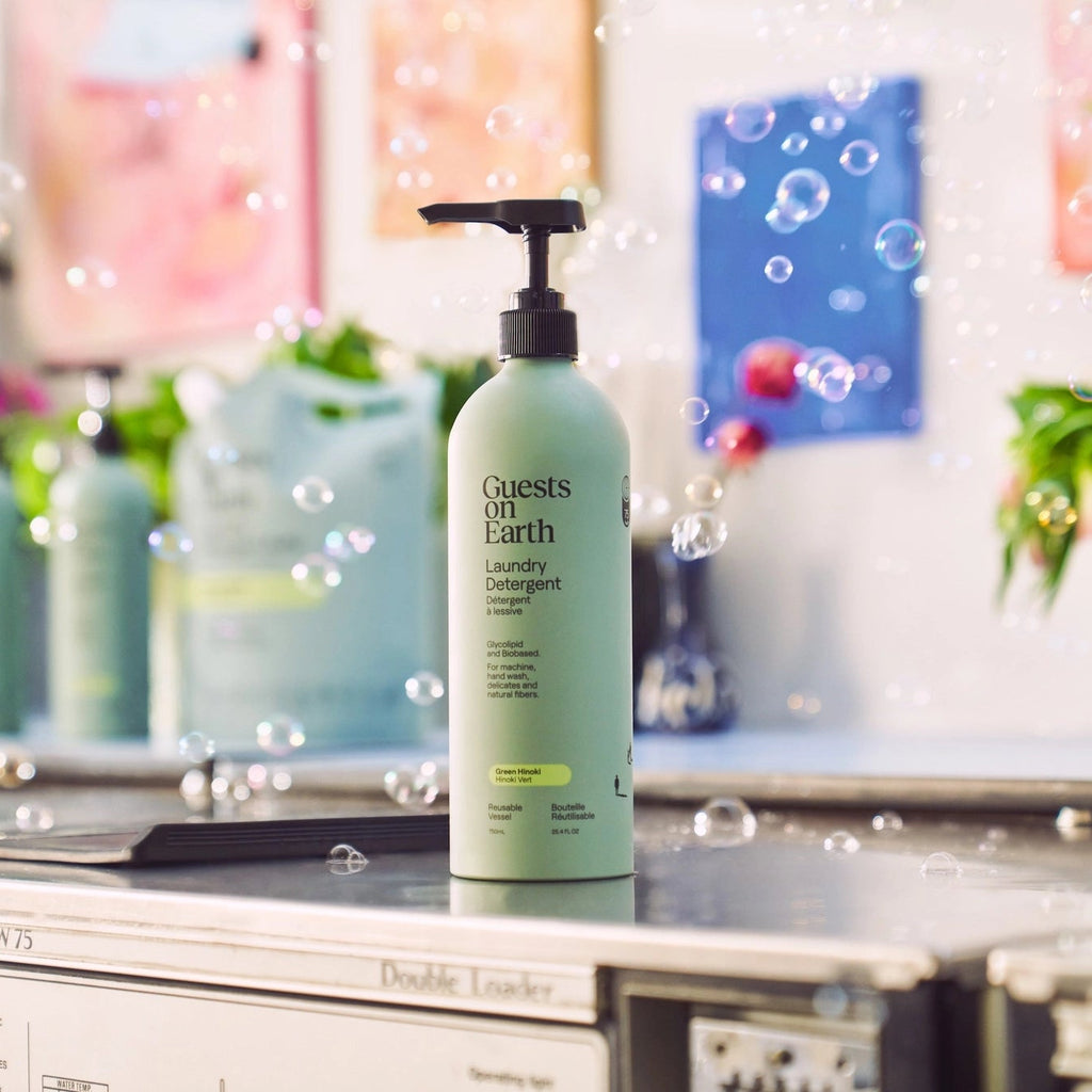 Green bottle labeled 'Guests on Earth' on a surface with blurred background