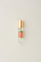 Small glass bottle with gold cap and colorful label on a light gray background