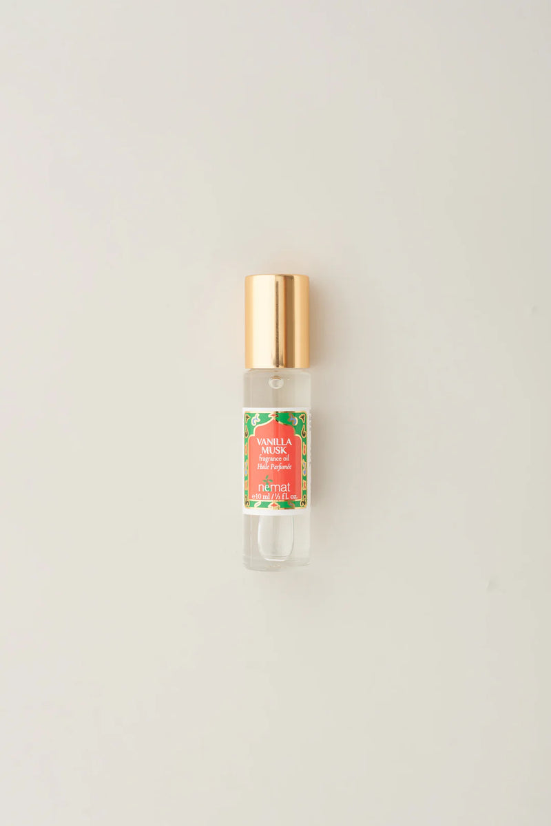 Small glass bottle with gold cap and colorful label on a light gray background