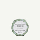 Round container with green patterned lid and white label on a white background